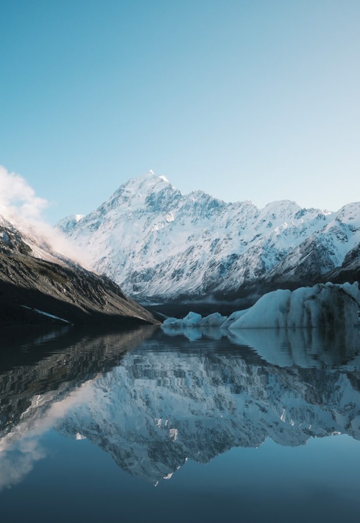 A mountain range is reflected in the still water of a lake